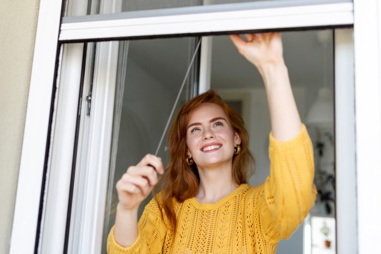 Woman hand hold retractable pleated insect screen holder to open or close the window ,mosquito nets